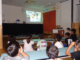 真っ暗になった部屋で映画を観る子どもたち