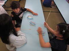 キラキラテープで作ったパーツを竹ひごに通すところ