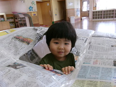 新聞紙ドームから顔を出す男の子