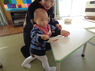 女児がでんでん太鼓を回しているところ