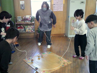 子どもたちがベーゴマを教えてもらっているところ